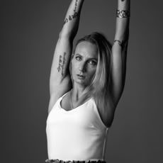 Monochrome image of a woman in white tank top stretching her arms.